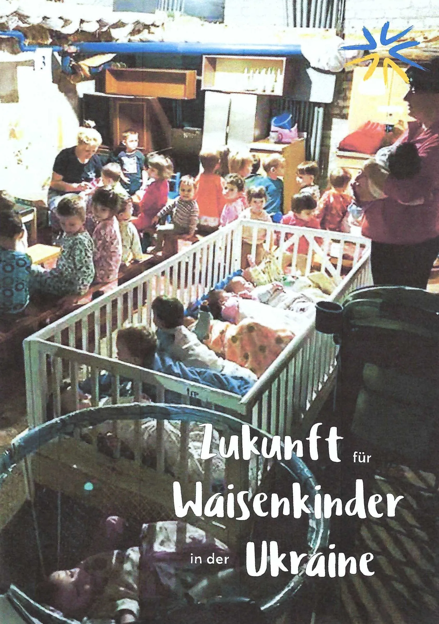 Eine Gruppe kleiner Kinder, einige in Kinderbetten, andere sitzend oder stehend, befindet sich in einem überfüllten Raum. Der deutsche Text lautet: Zukunft für Waisenkinder in der Ukraine (Zukunft für Waisenkinder in der Ukraine).