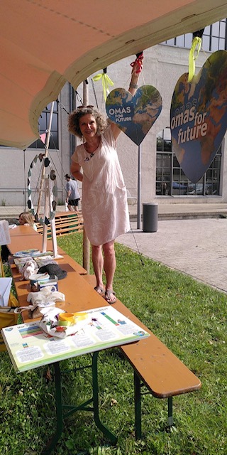 Mitglied der Omas for Future München dekoriert Herz-Banner am Infostand im Freien