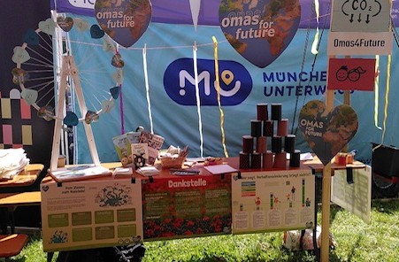 Infostand der Omas for Future München mit Spielen, Plakaten und Herz-Bannern auf einer Freiluftveranstaltung